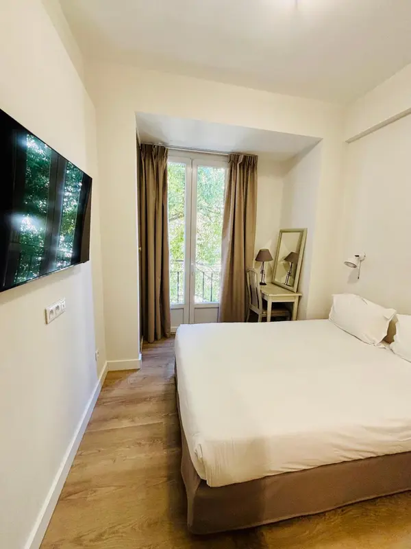 Une chambre lumineuse avec un lit et un bureau près d'une fenêtre.