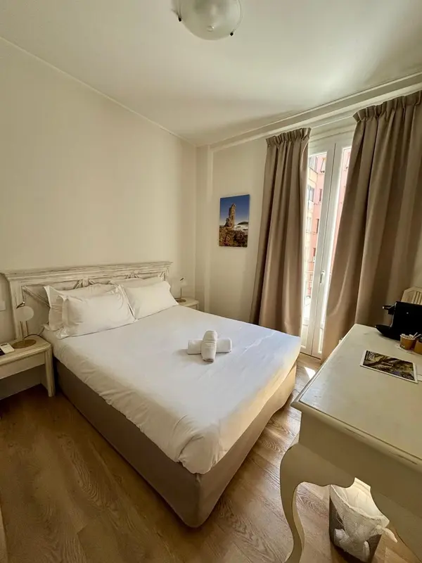 Chambre lumineuse avec un grand lit et une fenêtre.