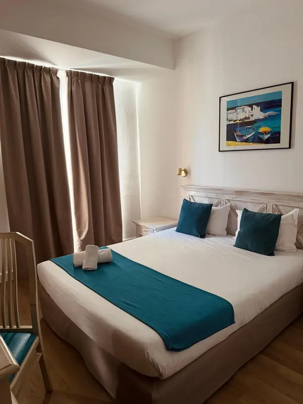 Une chambre lumineuse avec un grand lit recouvert d'une courtepointe turquoise.