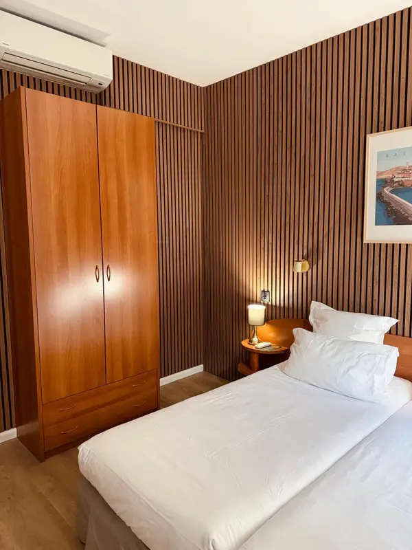 Une chambre lumineuse avec un lit simple et une armoire en bois.