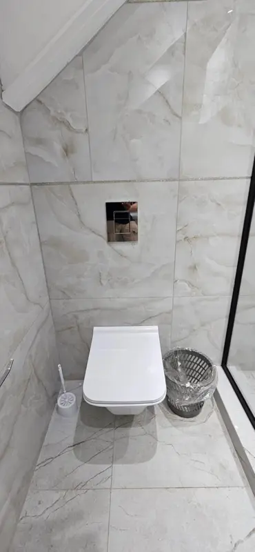 Une salle de bain moderne avec des carreaux de marbre et des sanitaires blancs.