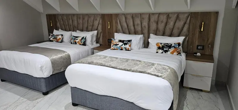 Deux lits jumeaux avec une décoration soignée dans une chambre.