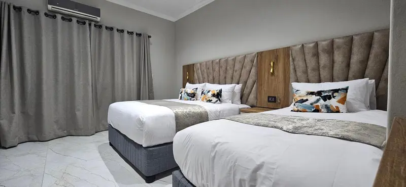 Deux lits jumeaux avec oreillers et couvertures dans une chambre décorée.