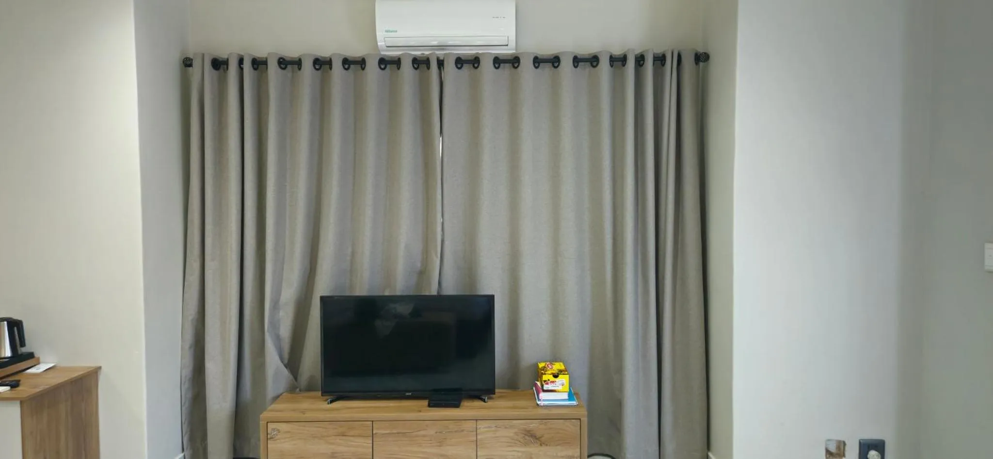 Une télévision posée sur un meuble en bois devant des rideaux.