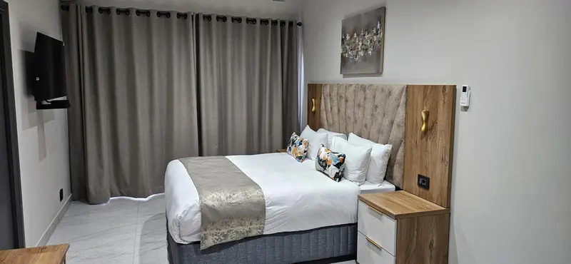 Une chambre lumineuse avec un grand lit et des rideaux gris.