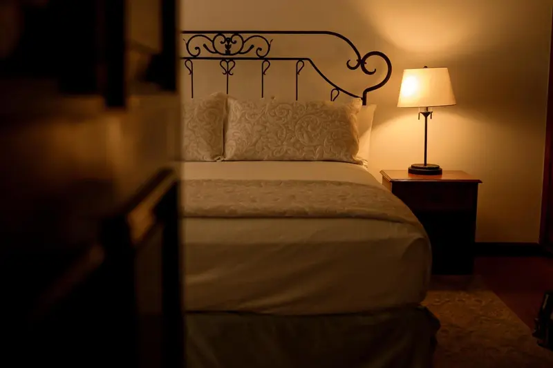 Un lit avec une tête de lit en fer forgé et une lampe de chevet.