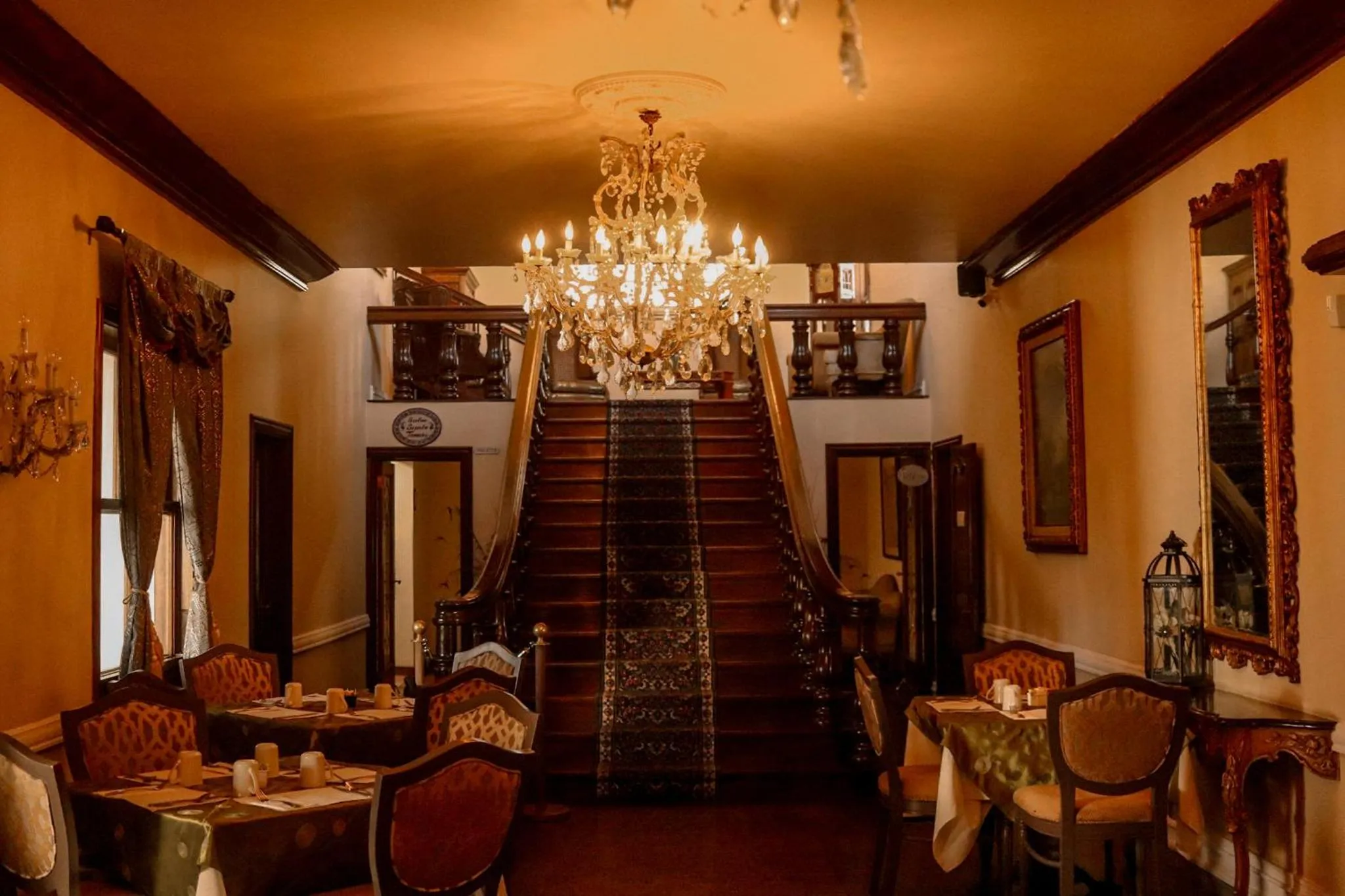 Une salle à manger élégante avec un escalier en bois et un lustre.