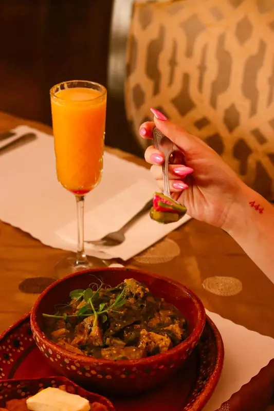 Une assiette de nourriture est servie avec une boisson orangée sur une table.