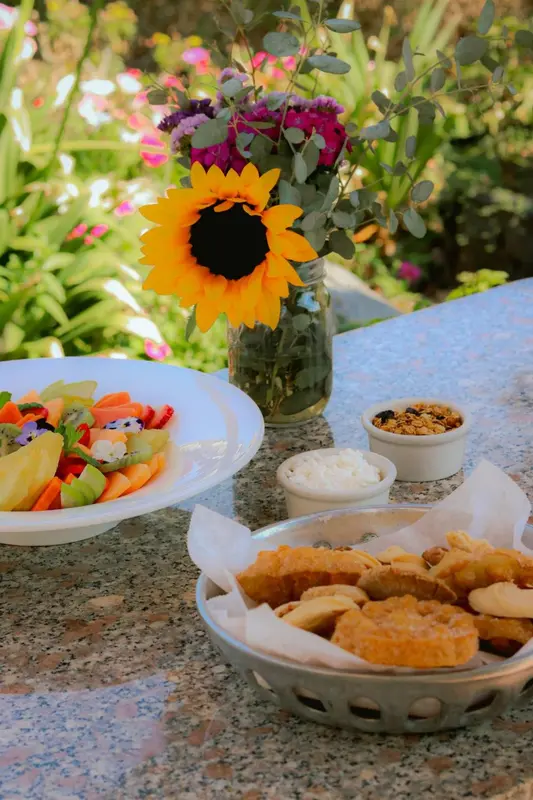 Assiette de fruits frais et viennoiseries sur une table en extérieur.