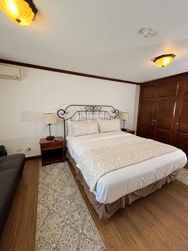 Une chambre lumineuse avec un grand lit recouvert d'une courtepointe décorative.