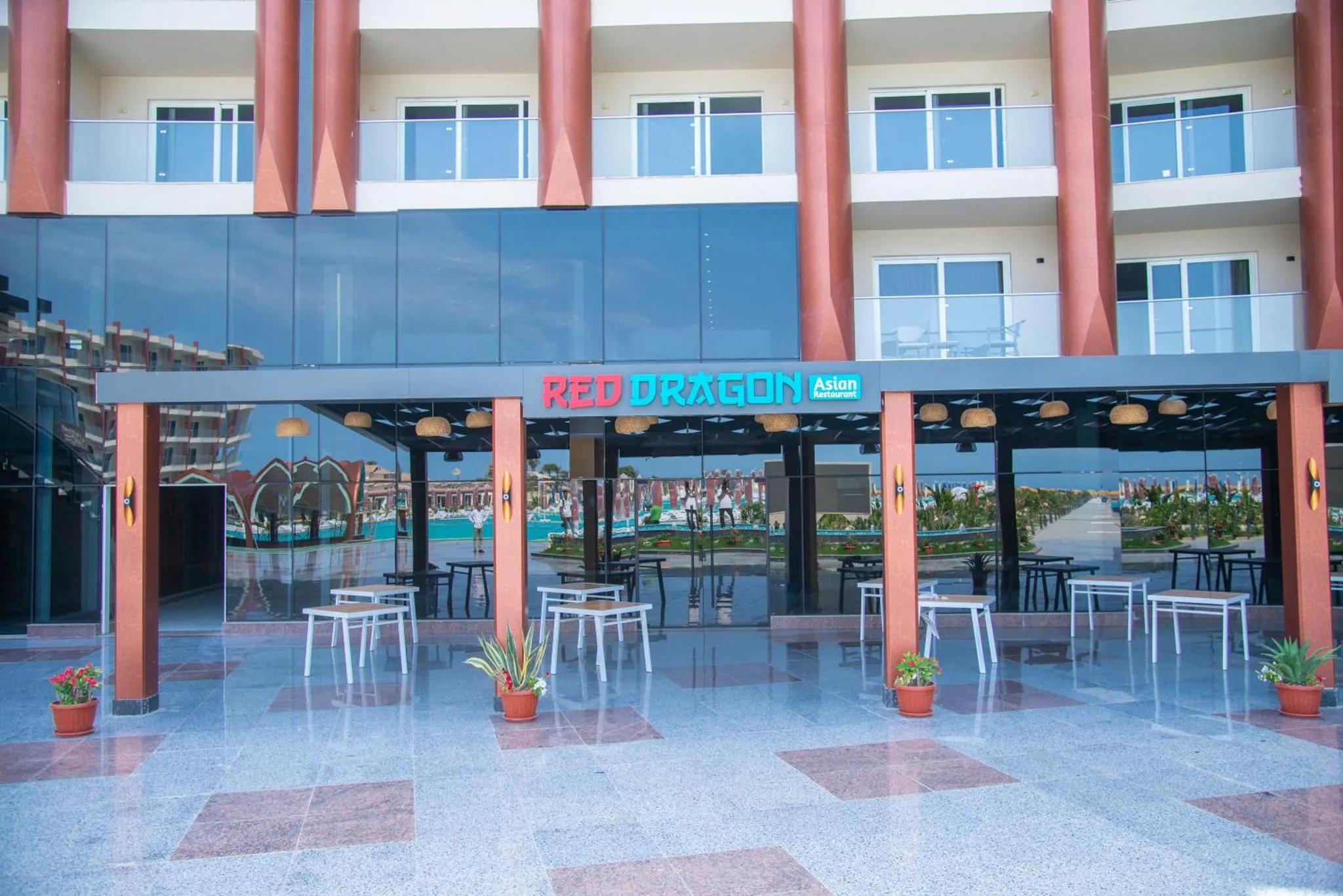 Terrasse d'un restaurant avec tables et chaises devant une façade vitrée.