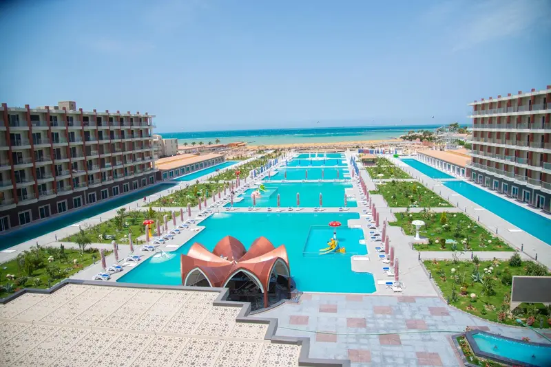 Vue aérienne d'un complexe hôtelier avec de grandes piscines et des bâtiments bas.