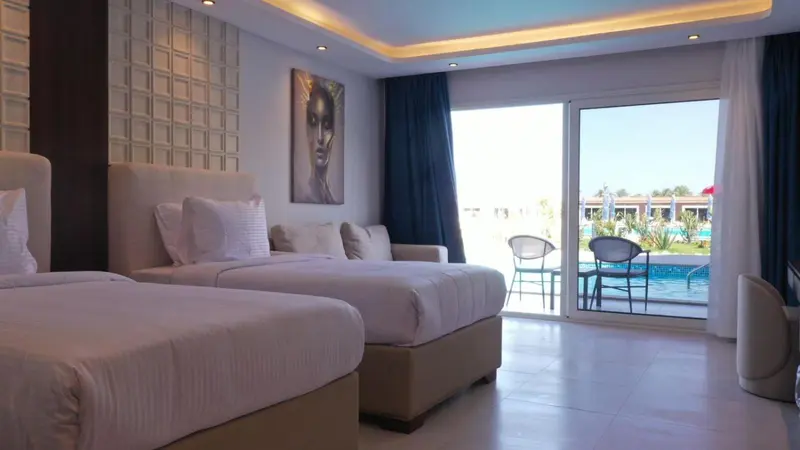 Une chambre lumineuse avec deux lits et une vue sur une piscine.
