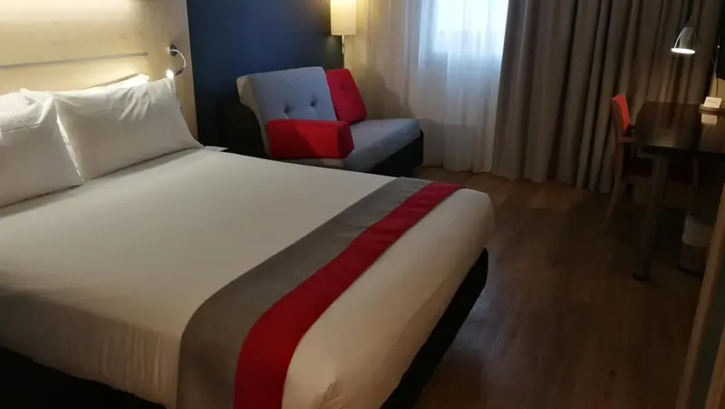 Une chambre lumineuse avec un lit double et un coin salon.