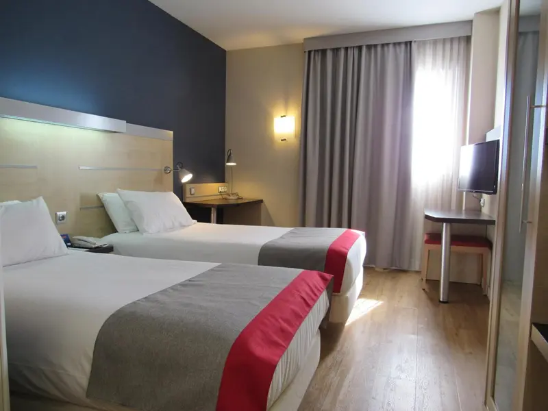 Une chambre d'hôtel avec deux lits simples et un bureau.