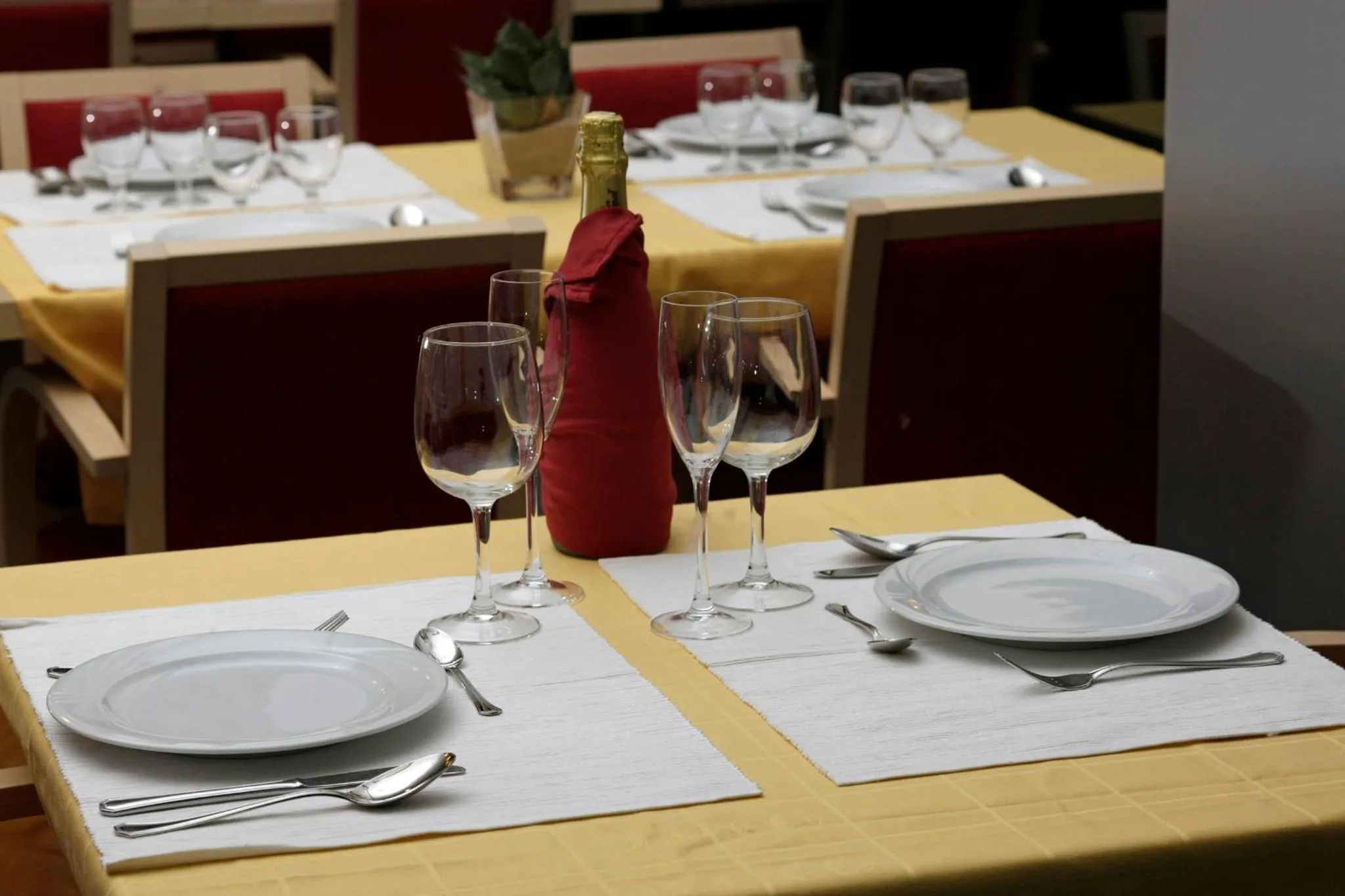Une table est dressée avec de la vaisselle et des verres dans une salle lumineuse.