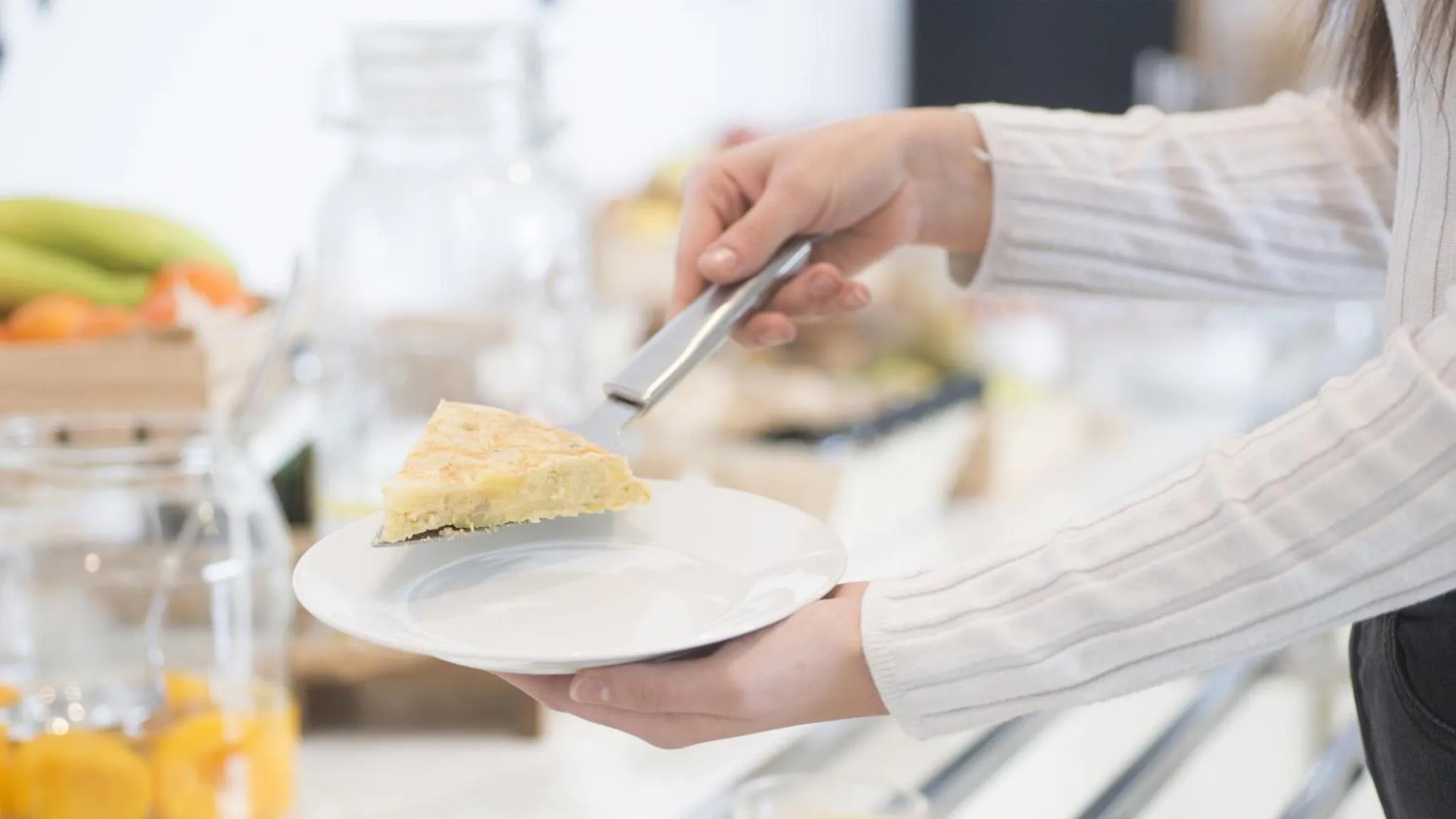 Une personne coupe une part de gâteau sur une assiette.