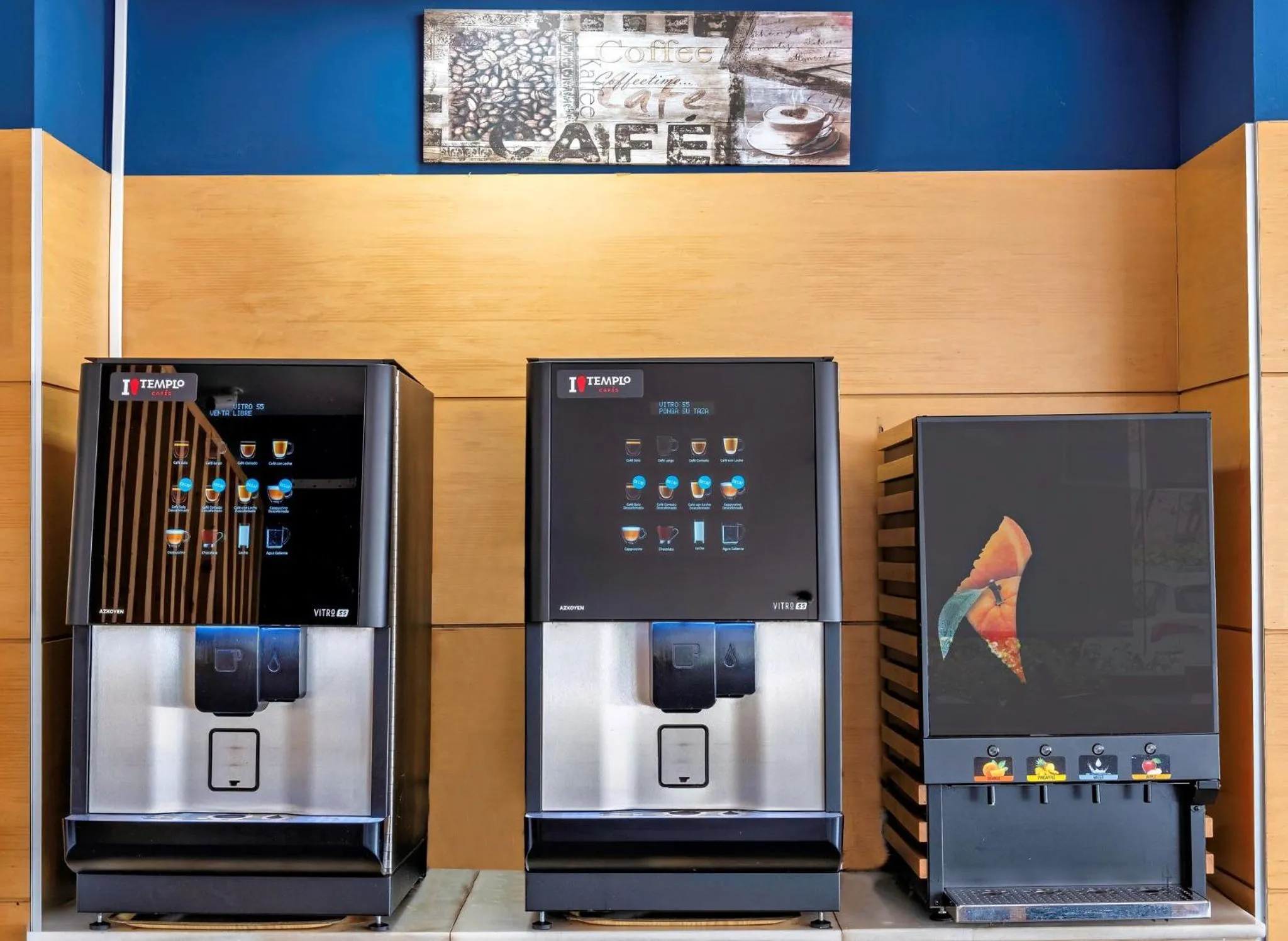 Trois distributeurs automatiques de boissons chaudes se trouvent contre un mur décoratif.