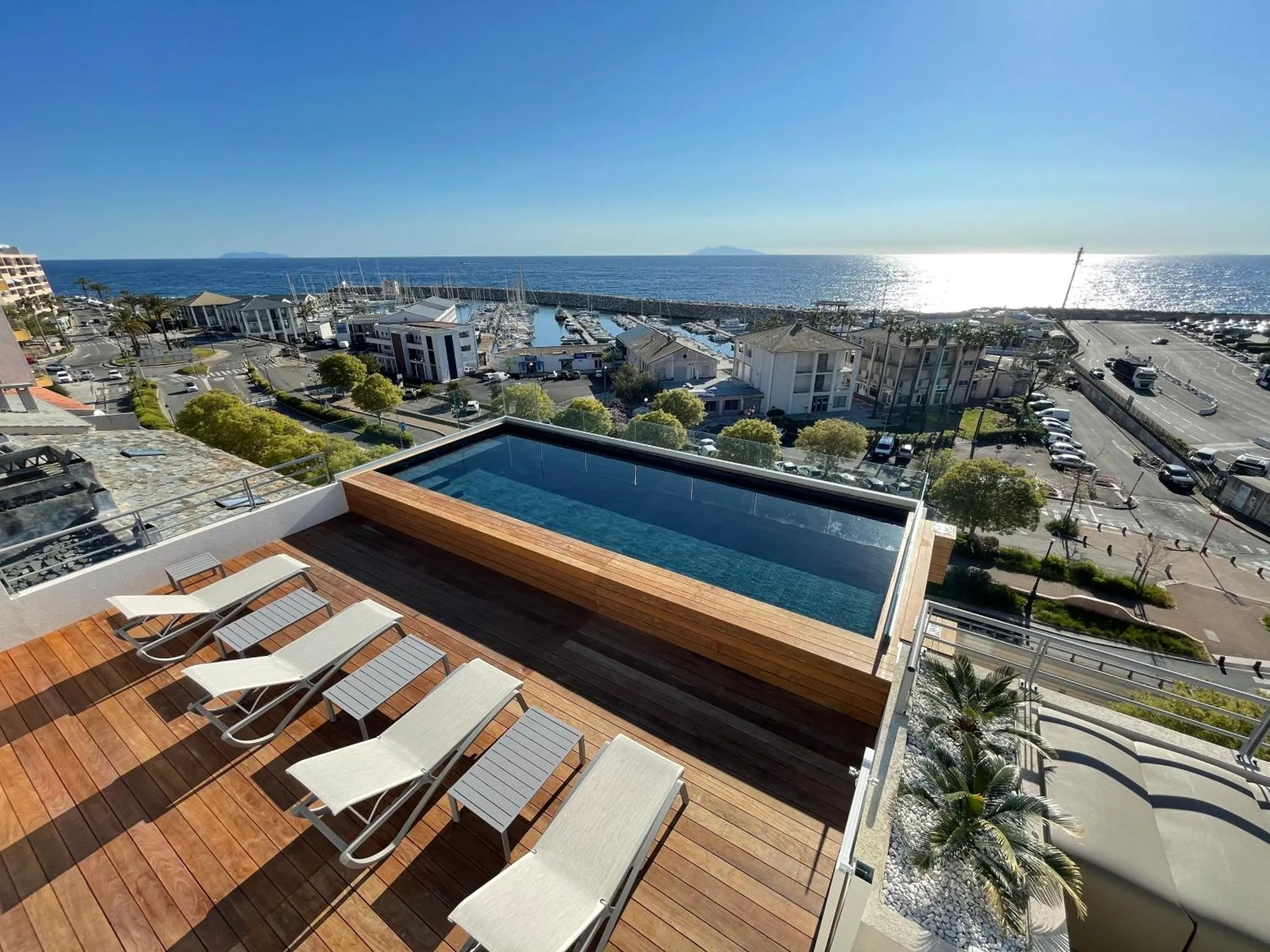 Terrasse avec transats et piscine à débordement surplombant la mer.