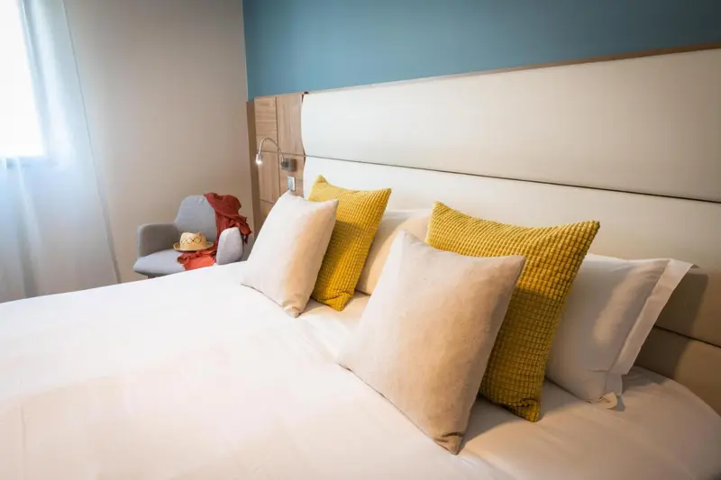 Un lit recouvert de coussins blancs et jaunes dans une chambre.
