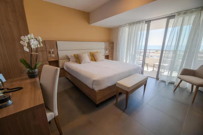 Chambre lumineuse avec un grand lit et une vue sur la mer.