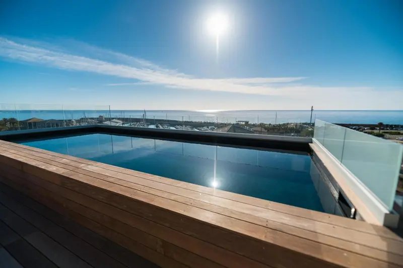 Une piscine à débordement offre une vue dégagée sur la mer et le ciel bleu.