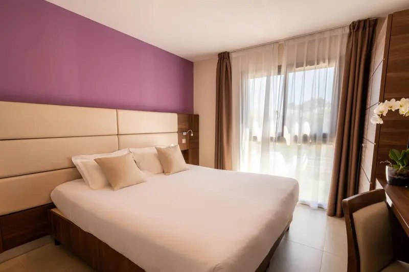 Une chambre lumineuse avec un grand lit et un accès à une terrasse.