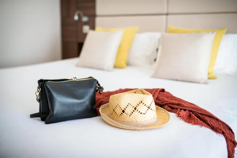 Un lit recouvert de draps blancs avec des oreillers et des accessoires de plage.