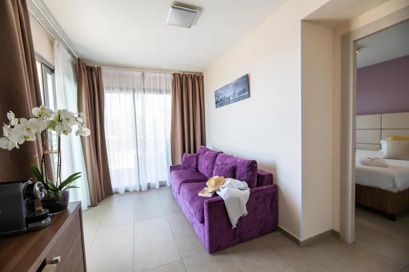 Espace de détente avec canapé violet et accès à une chambre.