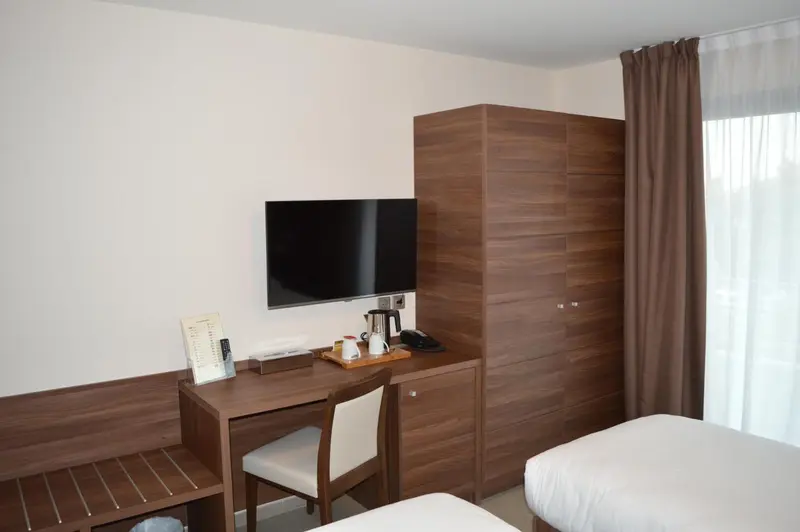Une chambre d'hôtel lumineuse avec un bureau et une télévision murale.