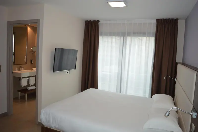 Une chambre lumineuse avec un lit et un accès à une salle de bain.