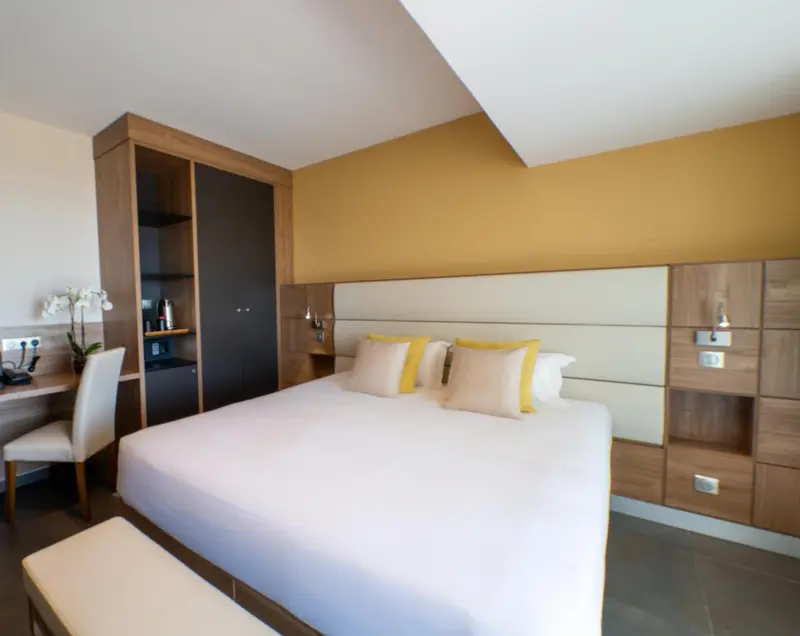 Une chambre lumineuse avec un grand lit et un espace bureau.