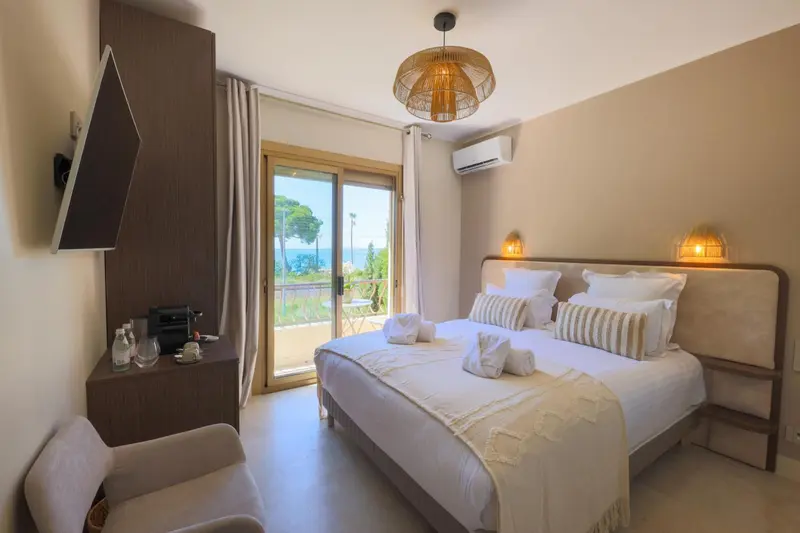 Chambre lumineuse avec un grand lit et vue sur la mer.