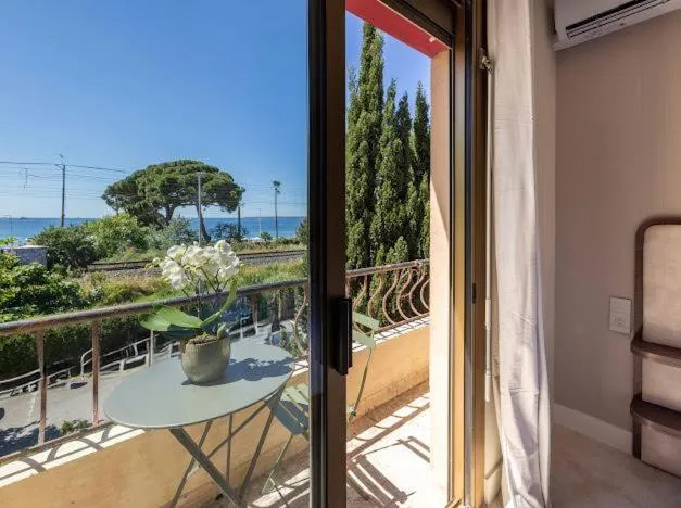 Une terrasse avec une table ronde et une vue sur la mer et la végétation.