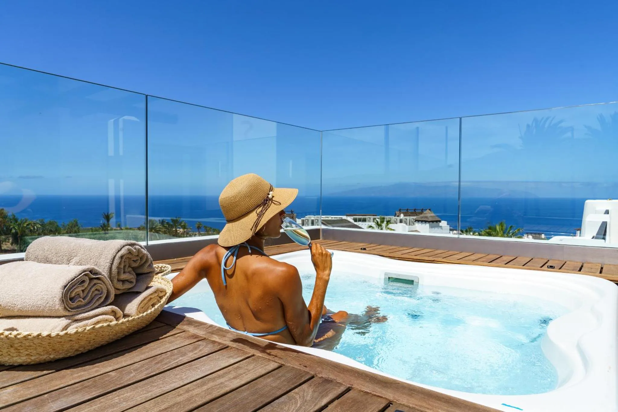Une personne se détend dans un jacuzzi sur une terrasse avec vue sur la mer.