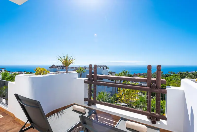 Terrasse avec transats donnant sur une vue mer et végétation.