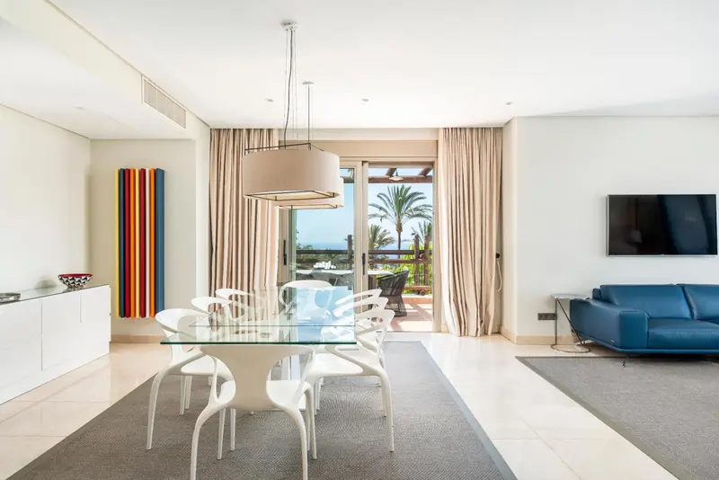 Espace de vie lumineux avec table à manger et canapé face à une vue sur la mer.