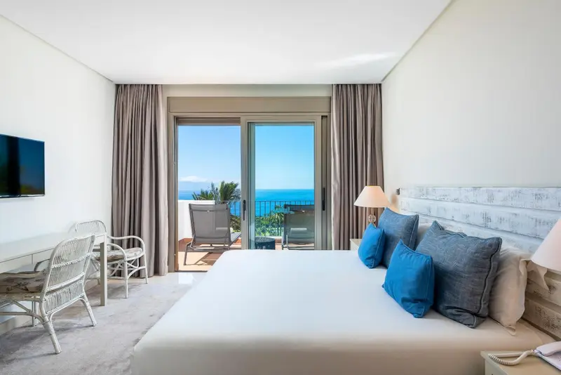 Une chambre lumineuse avec un grand lit et une vue sur la mer.