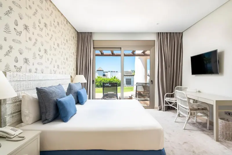 Une chambre lumineuse avec un grand lit et un accès à une terrasse.