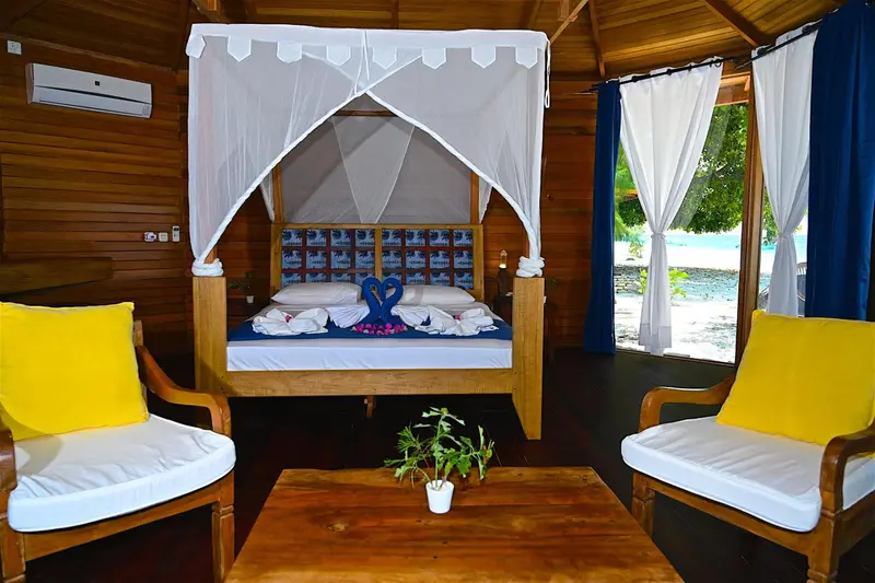 Une chambre avec un lit à baldaquin et deux fauteuils.