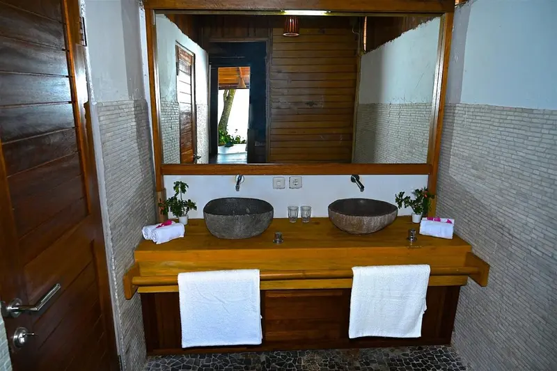 Une salle de bain avec deux vasques en pierre et un miroir mural.