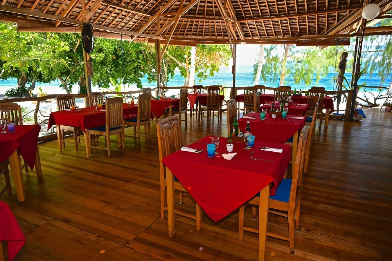 Une salle à manger extérieure avec des tables dressées face à la mer.