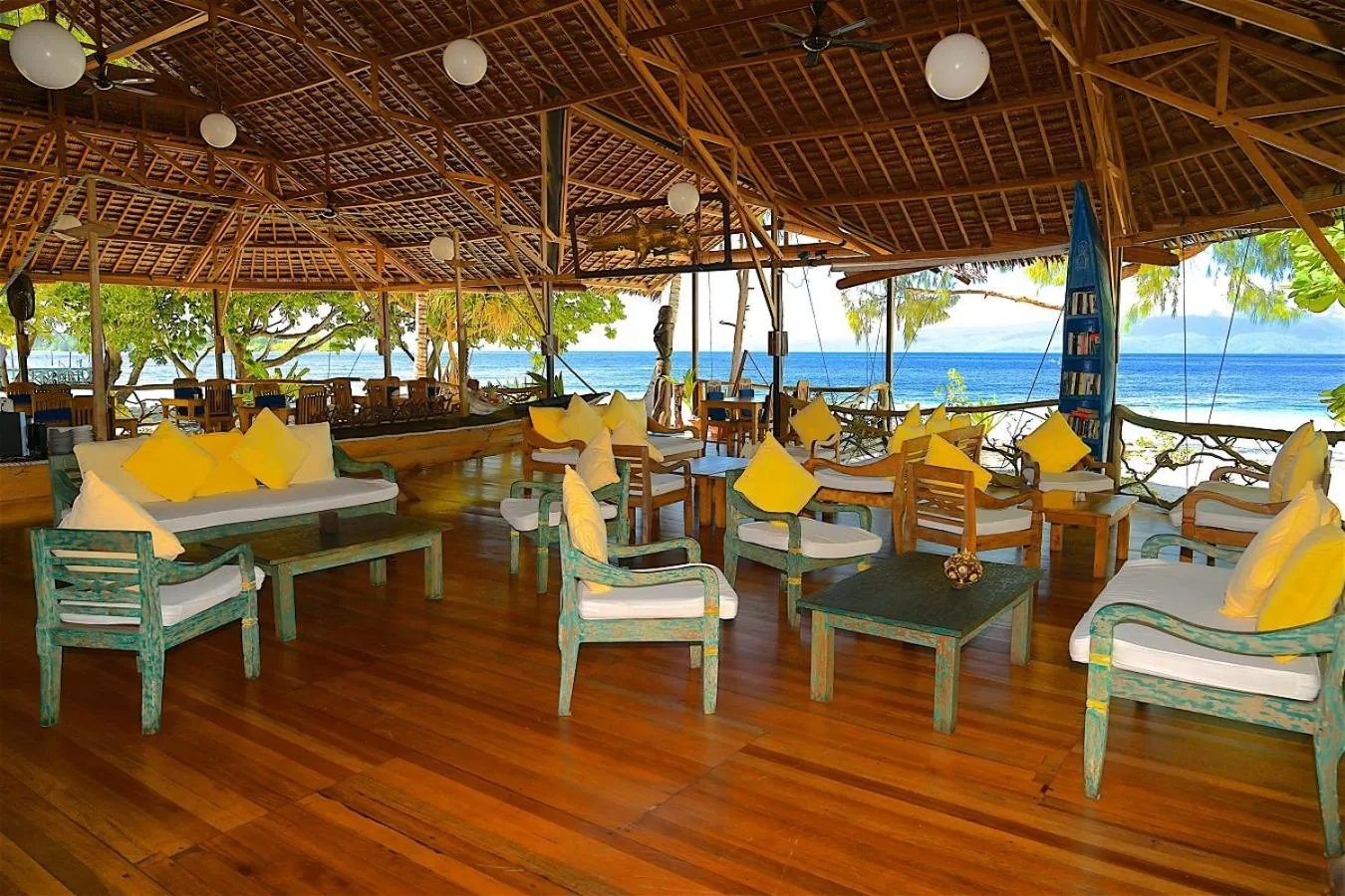 Espace de détente extérieur avec mobilier en bois et vue sur la mer.