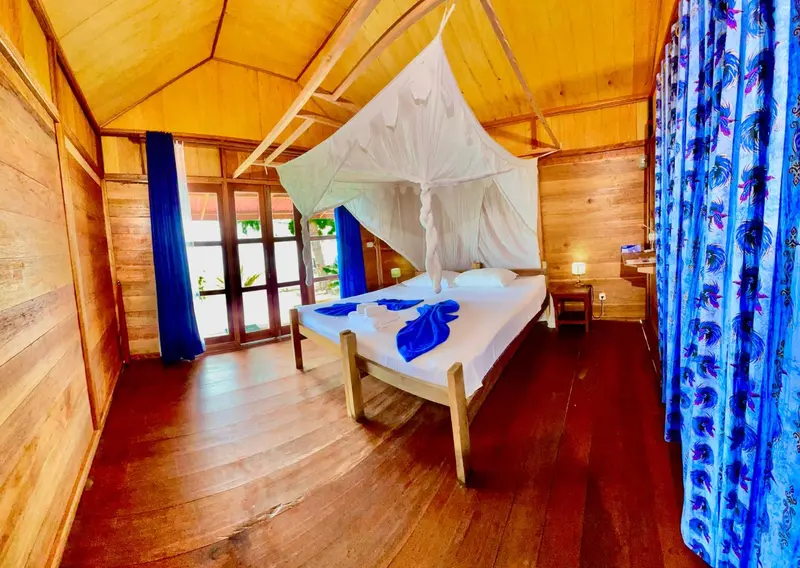 Une chambre lumineuse avec un lit à baldaquin et un sol en bois.
