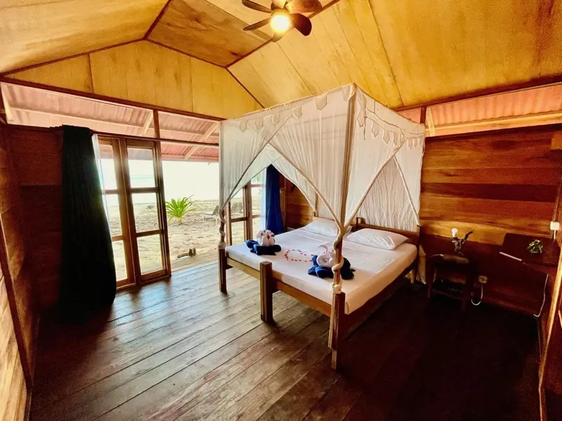 Une chambre avec un lit à baldaquin donnant sur une plage.