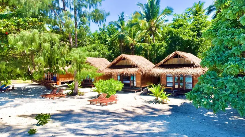 Cabanes de plage traditionnelles bordées de végétation tropicale.