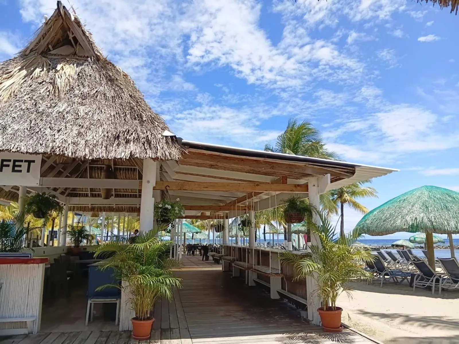 Terrasse ombragée avec mobilier de jardin face à la mer.