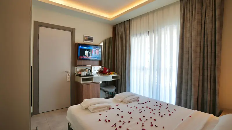 Une chambre d'hôtel lumineuse avec un lit décoré de pétales de fleurs.