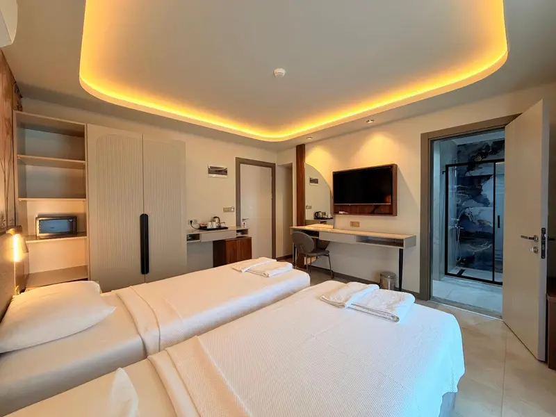 Chambre lumineuse avec deux lits simples et un bureau.