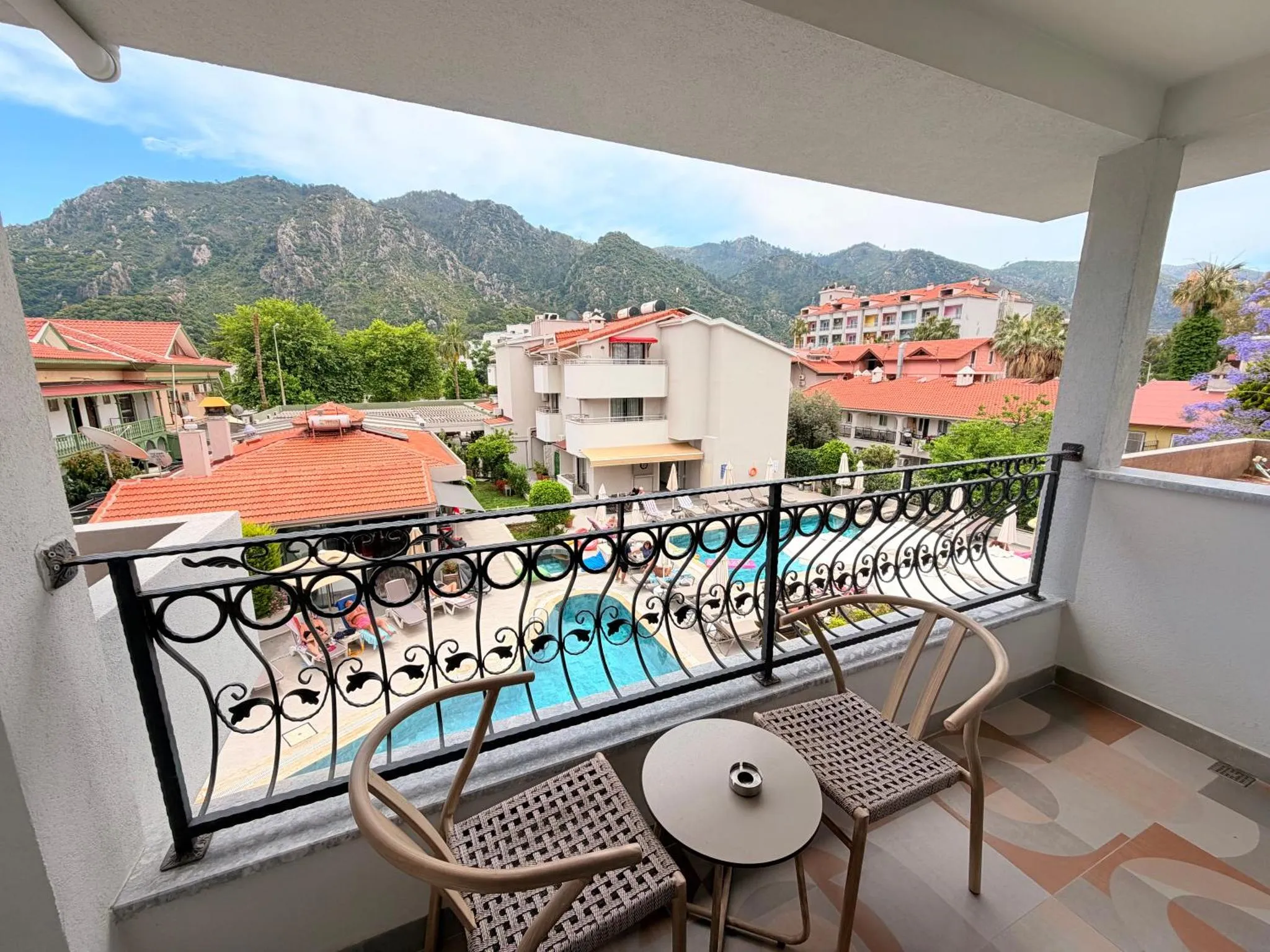 Vue d'une terrasse avec mobilier donnant sur une piscine et des montagnes.